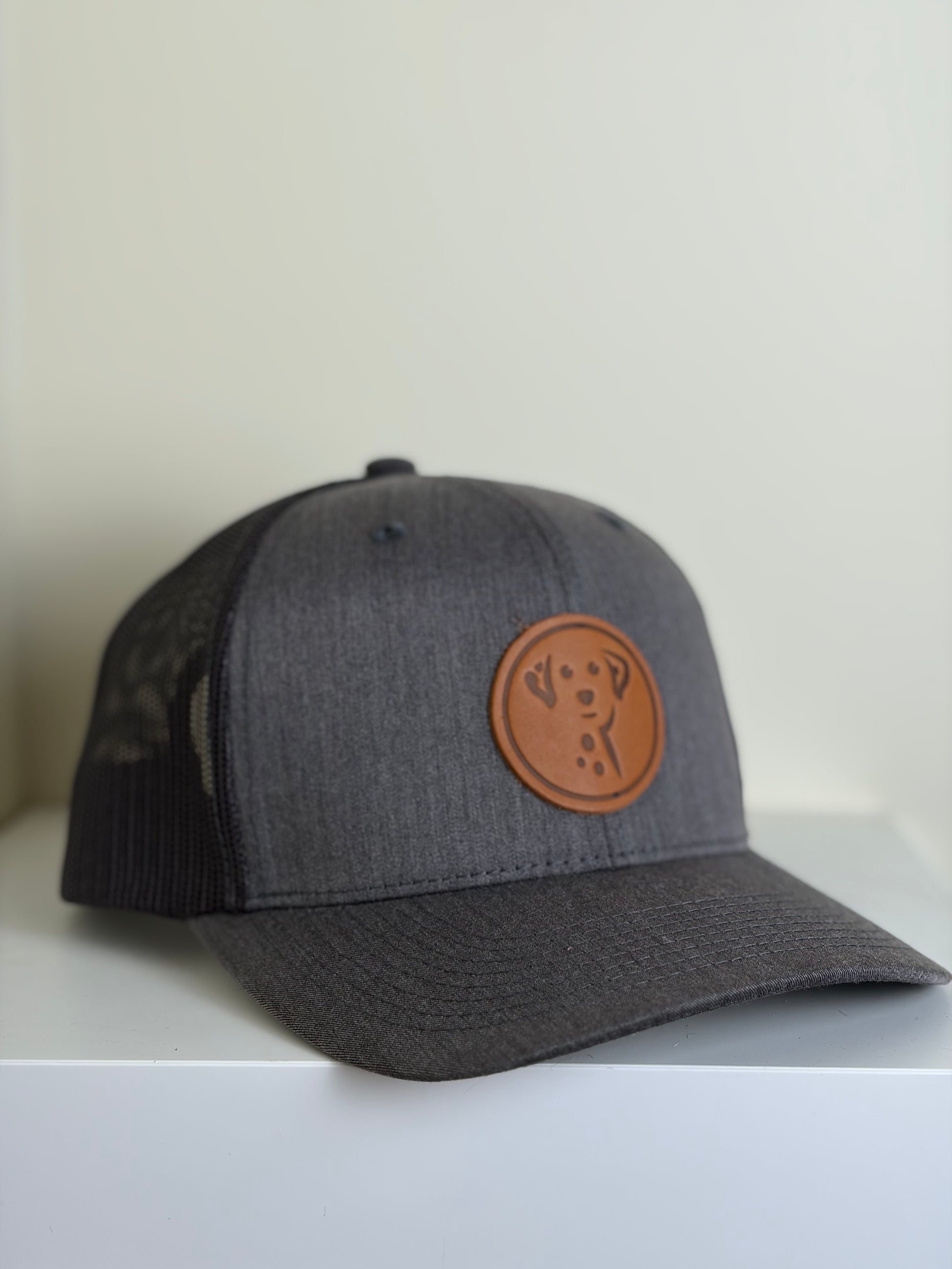 Gray cap with a brown leather patch on a white surface