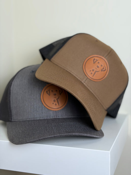 Two baseball caps with leather patches on a white surface
