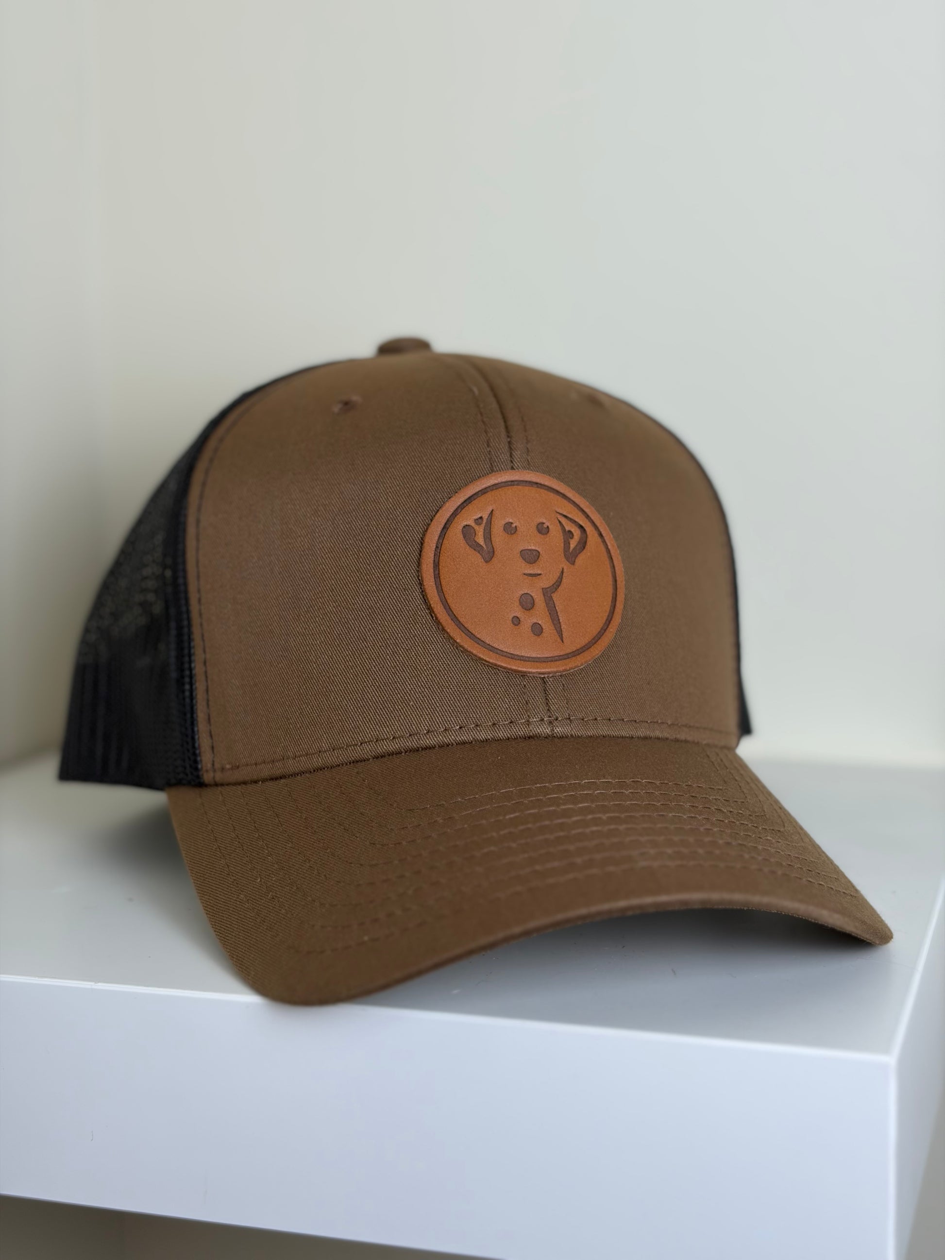 Brown and black cap with a circular patch on a white surface